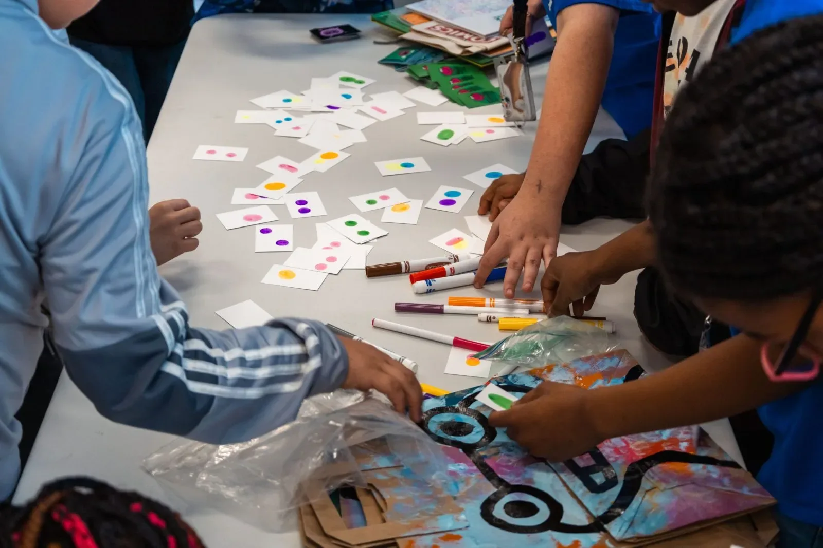 A group of children drawing with makers on small cards.
